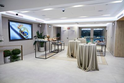 espacio castellana otro ángulo de las mesas altas y buffet, con la puerta llevando a la vista al terreno de juego al fondo